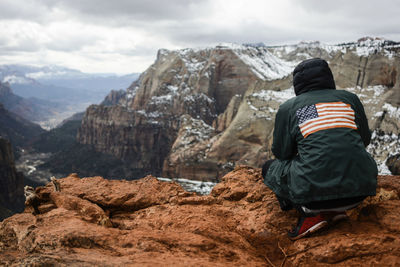 Woman standing on rock by mountains against sky