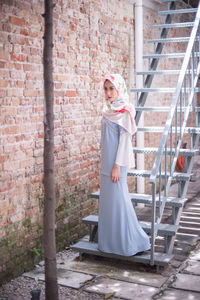 Portrait of happy woman standing against brick wall