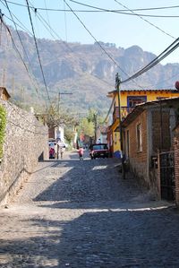 Road amidst buildings and mountains against sky
