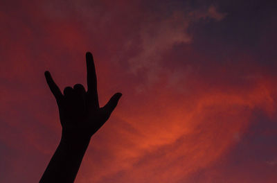 Silhouette of hand against red sky