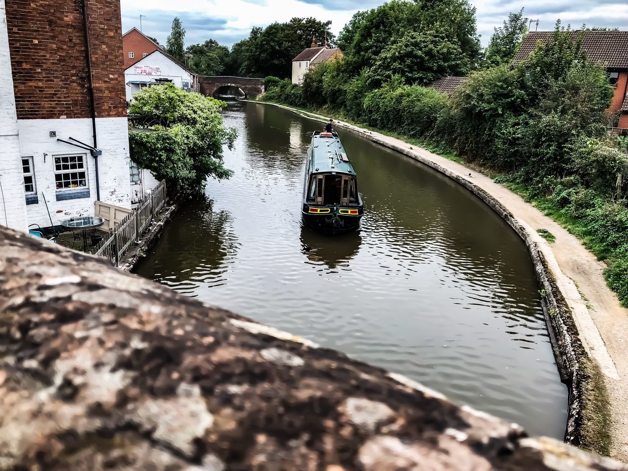 REAR VIEW OF MAN IN BOAT ON CANAL BY HOUSE