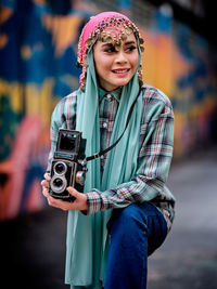Beautiful asian female posing with a retro camera