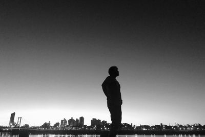 Silhouette man standing on city against clear sky