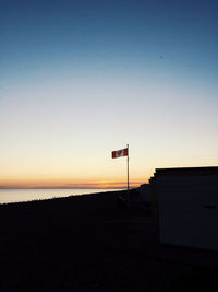 Silhouette road by building against clear sky during sunset