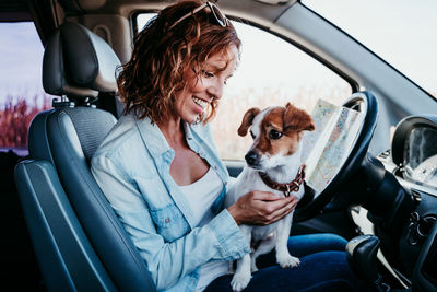 Woman holding dog sitting in car