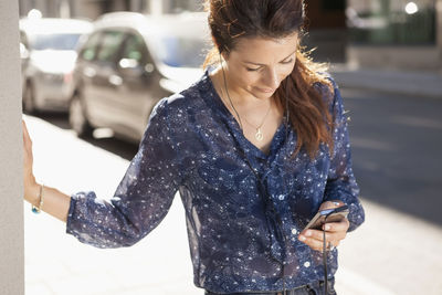 Businesswoman using mobile phone on street