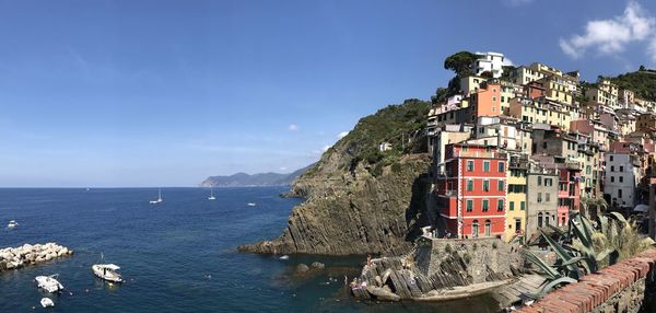 Buildings by sea against blue sky