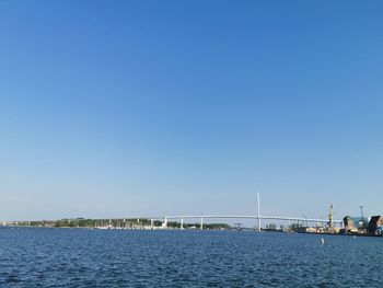 Bridge over sea against clear blue sky