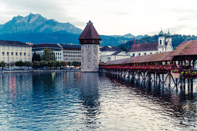 Bridge over river by buildings in city against sky