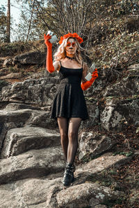 Full length portrait of woman standing against wall