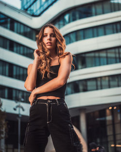 Beautiful young woman standing against building in city