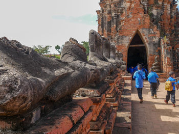 Rear view of people outside temple against sky