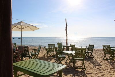 Chairs and table at beach against sky