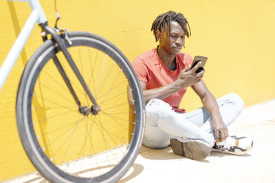Ethnic man using smartphone near bicycle