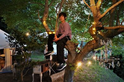 Portrait cute boy sitting on tree