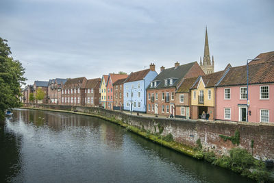 Buildings by river against sky in town