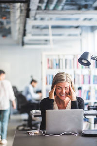 Woman using mobile phone while sitting in office