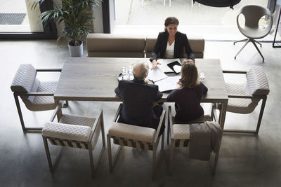 High angle view of female lawyer and customers sitting at desk in office