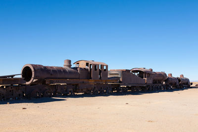 Old train on desert against clear blue sky