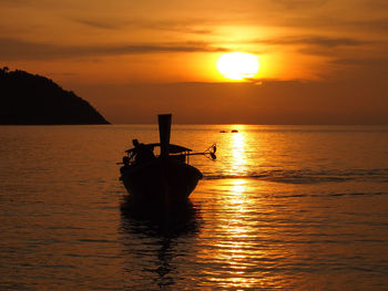 Silhouette boat in sea against sky during sunset