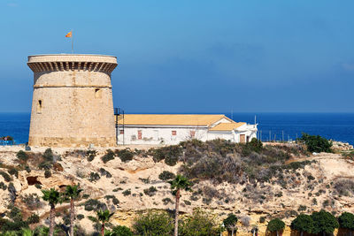 View of built structure by sea against sky