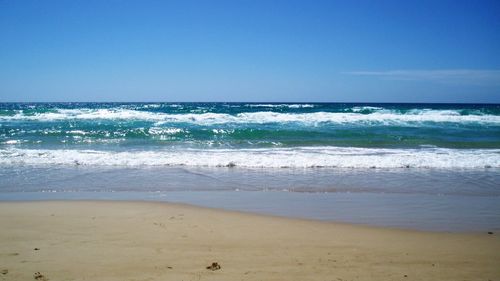 Scenic view of beach against blue sky