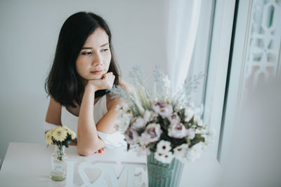 Woman sitting by flowers at home