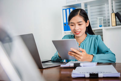 Young woman using mobile phone while sitting on table