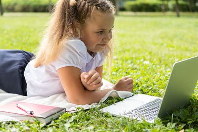 Young woman using laptop while sitting on field