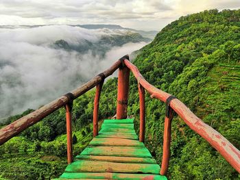 Footbridge amidst mountains against sky