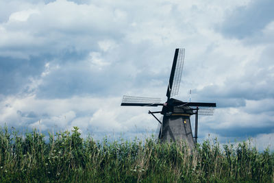 Low angle view of traditional windmill on field against sky