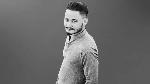 Portrait of young man standing against black background