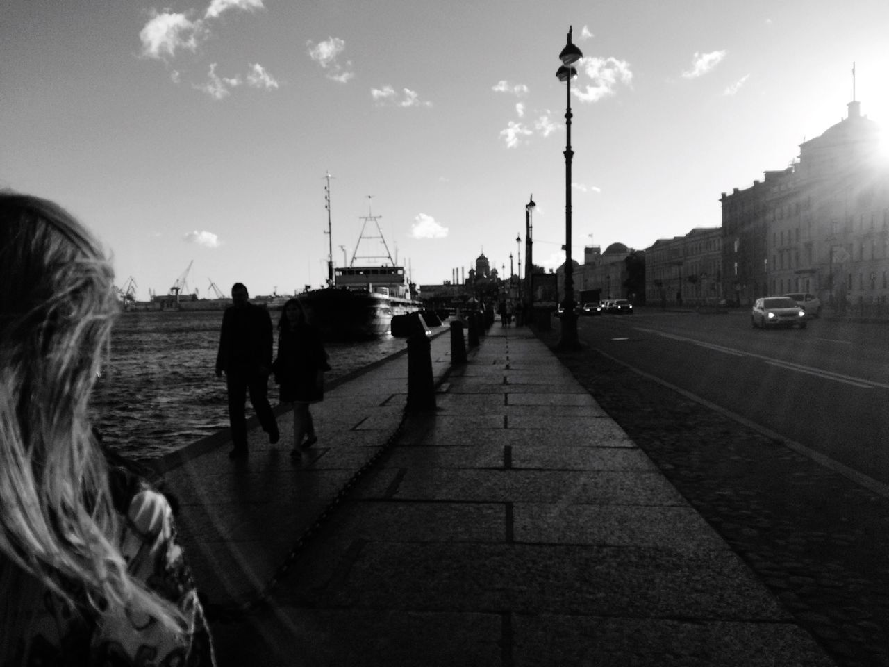 sky, transportation, mode of transport, car, street light, walking, built structure, land vehicle, building exterior, architecture, men, cloud, travel destinations, day, footpath, outdoors, city life, cloud - sky, tourism, the way forward