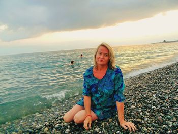 Young woman on beach against sky during sunset