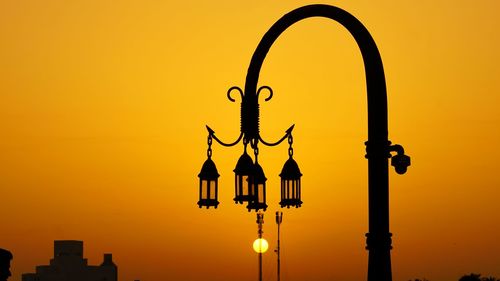 Silhouette street light against orange sky