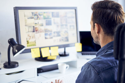 Photo editor working on computer at desk in office