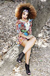 Fashion model in a summer dress posing on a tree