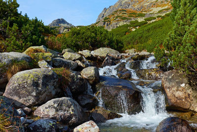 Stream flowing through rocks against sky