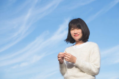 Portrait of smiling woman standing against sky