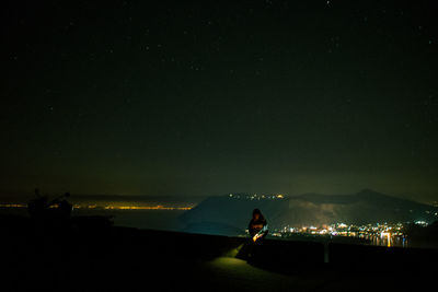 Silhouette people on illuminated city against sky at night