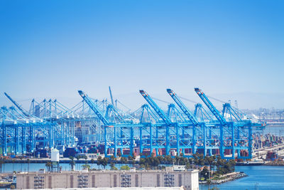 Commercial dock by sea against clear blue sky
