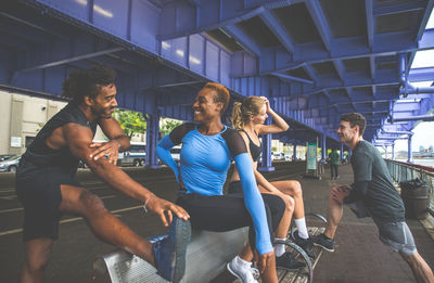 Friends exercising on bench in city