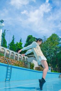 Man jumping in swimming pool against sky