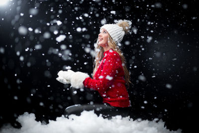 Side view of cheerful mid adult woman wearing warm clothing during snowfall