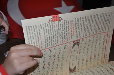 Close-up of hand holding book with text