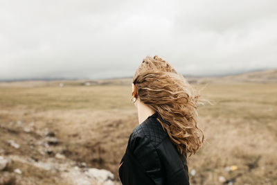 Rear view of woman standing on land against sky