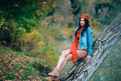 Portrait of smiling woman sitting on tree trunk