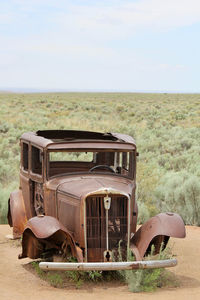 Abandoned truck on field against sky