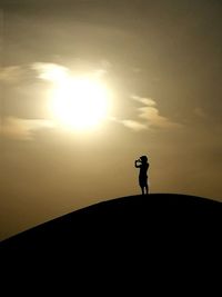 Silhouette man standing against sky during sunset