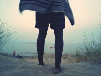 Low section of man standing on beach